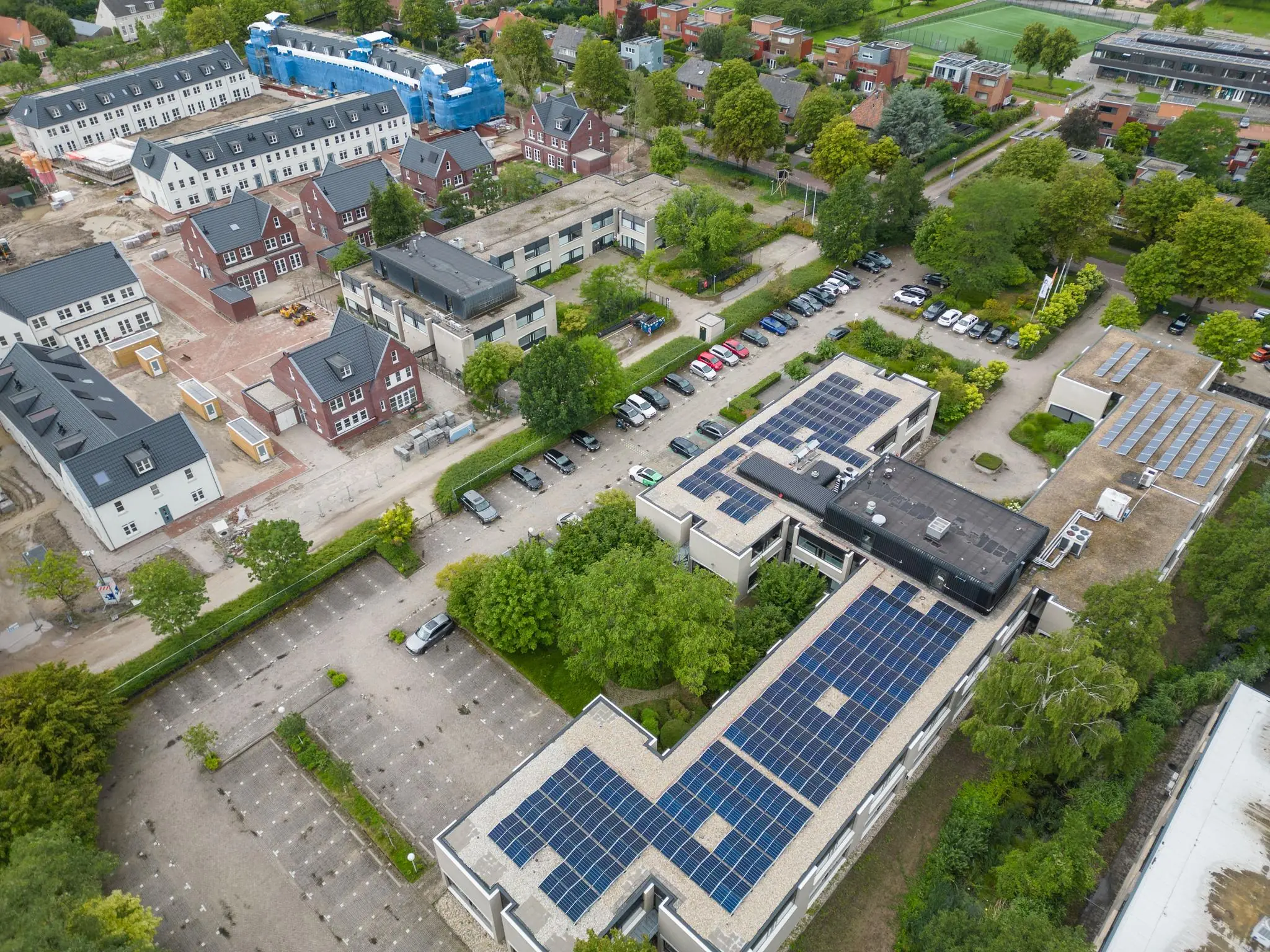 Luchtfoto van woonwijk en schoolgebouw met zonnepanelen aan de Burgemeester Verderlaan.